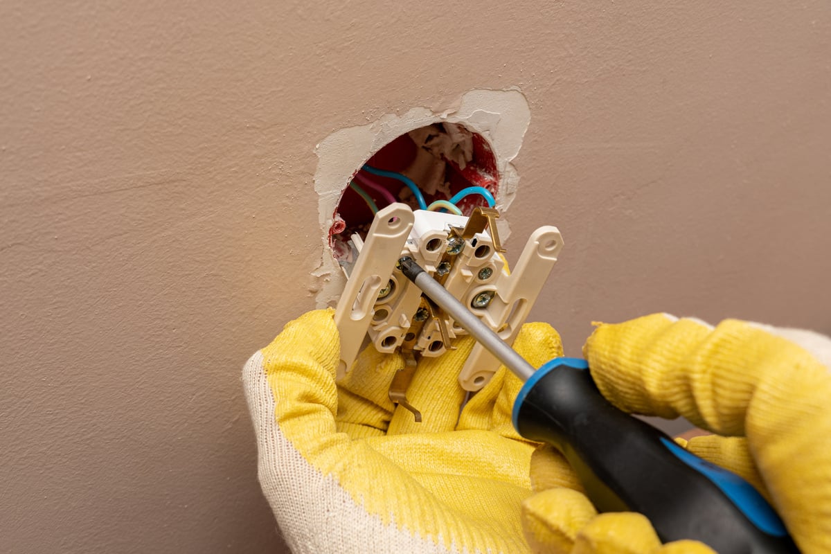 Replacing, installing an electrical socket, outlet with hands in protective rubber gloves